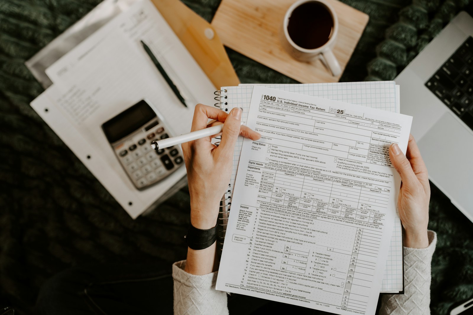 Person reviewing financial documents with a calculator and laptop